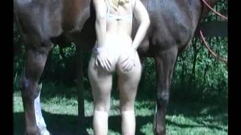 Naked blond woman in outdoor animal sex video with her horse