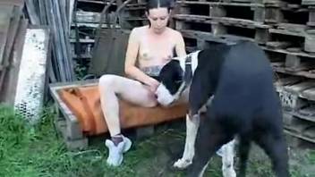 Dark-haired woman with small breasts having sex with a dog outside